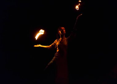 young woman doing fire show at night, motion blur of flam