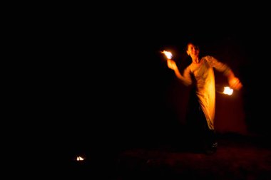 Genç bir kadın gece ateş gösterisi yapıyor. Hareket bulanıklığı.