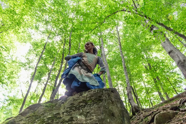 Esmer kadın ormanda bir taşın üzerinde duruyor, yaz, Ukraynalı Karpatyalı.