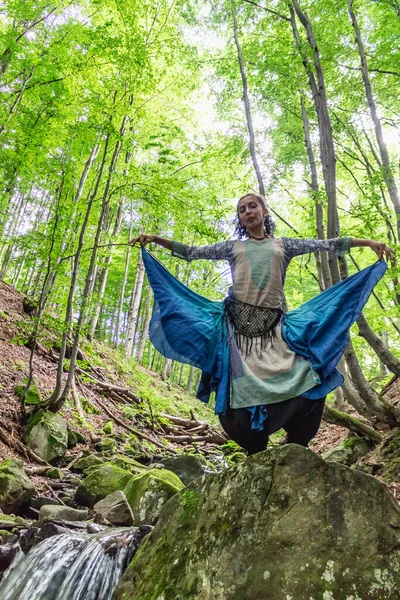 Esmer kadın ormanda bir taşın üzerinde duruyor, yaz, Ukraynalı Karpatyalı.