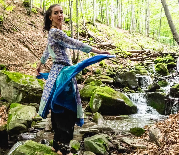 Dere kenarında dans eden esmer kadın, mavi kıyafetler, yaz, Karpatyalı.