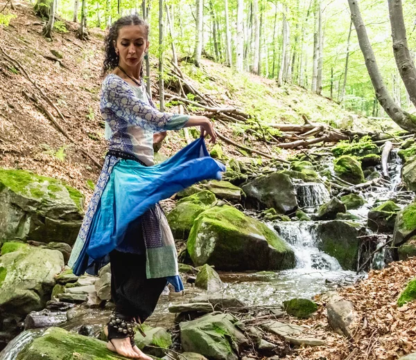 Dere kenarında dans eden esmer kadın, mavi kıyafetler, yaz, Karpatyalı.