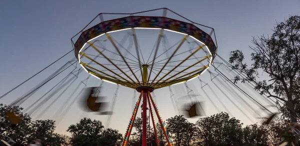 Akşamki eğlence parkında atlıkarınca hareket halinde, salıncak hareketinin bulanık görüntüsü