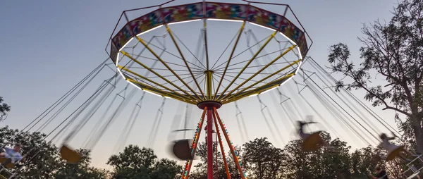 Akşamki eğlence parkında atlıkarınca hareket halinde, salıncak hareketinin bulanık görüntüsü