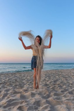 girl teenager plays sand on the Black Sea beach, summer vacatio