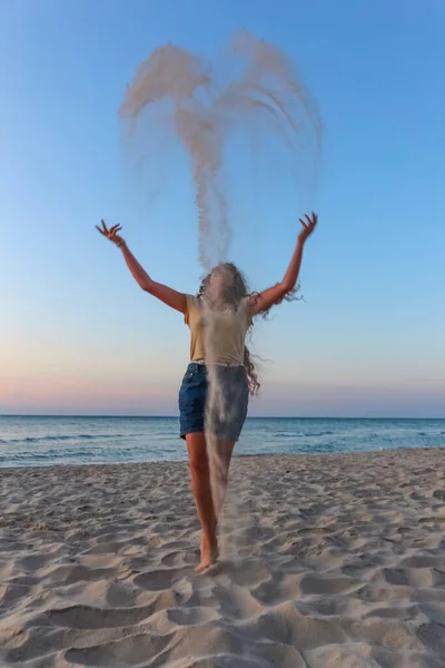 girl teenager plays sand on the Black Sea beach, summer vacatio