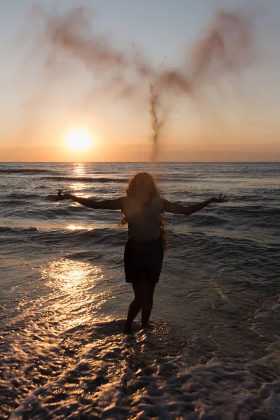 girl throws sand on the seashore, sunset on the beach, summe