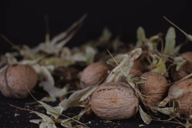 Ceviz ve yeşil-sarı yapraklar yakın plan. Siyah arka planda doğranmış fındıklar var. Kaliteli bir geçmişi var. Boşluğu kopyala