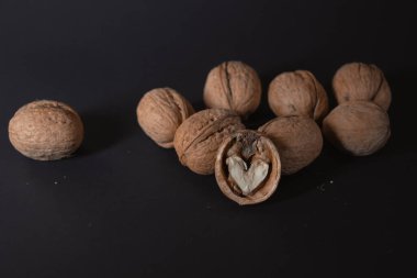 Ceviz ve yeşil-sarı yapraklar yakın plan. Siyah arka planda doğranmış fındıklar var. Kaliteli bir geçmişi var. Boşluğu kopyala