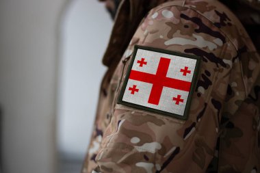 Georgia Askeri. Askeri üniformalı Gürcistan bayrağı taşıyan bir asker. Kamuflaj kıyafeti.