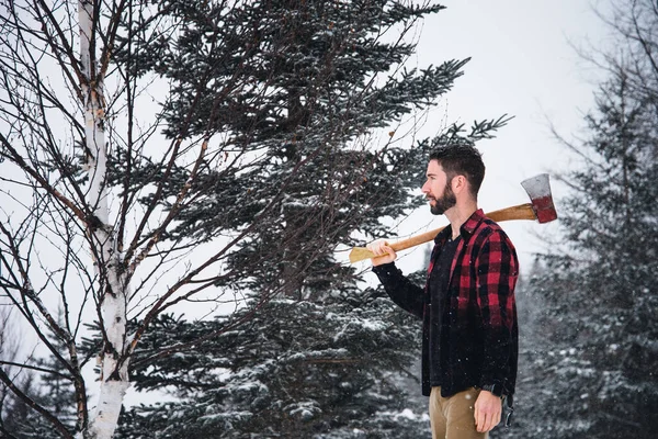 Young lumberjack man in the woods during winter time