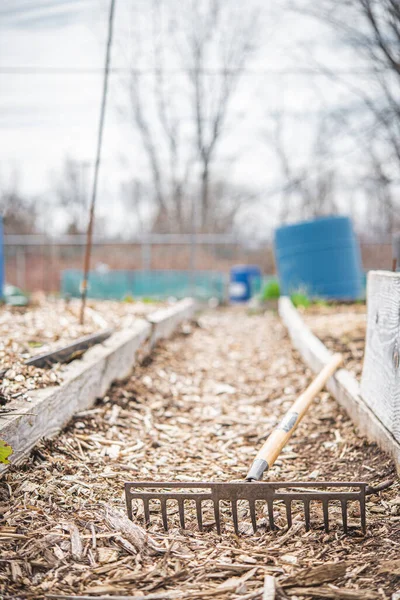 Gardening rake left on the floor of a community garden during a cloudy day 