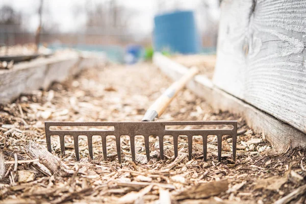 Gardening rake left on the floor of a community garden during a cloudy day 