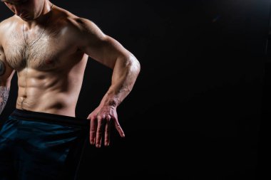 Siyah arka plandaki adam fitness aktif atlet eğitiminde halterleri şişirmeye devam ediyor atletik ağır, erkek göğüs kasları. Sportif spor salonu. Baskıya bak ve kilosu için pantolonun ölçüsünü al.