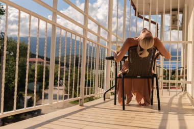 Kız, dağların balkonunda oturuyor ve mavi gökyüzü güzellik insanlarının arka planında güzel kadın, yetişkin, güzel güzellik salonu. İlham veren şehir dinlendirici, tatil oteli