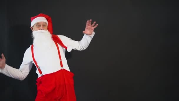 Santa Claus amarillo con estilo, tirantes navidad año nuevo, diciembre de edad. Sombrero de dieta baila alegremente sobre un fondo negro — Vídeos de Stock