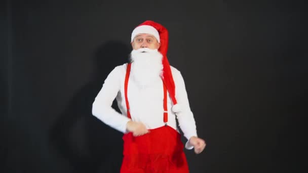 Babbo Natale giallo cibo elegante, bretelle festa Natale anno costume vecchio. Cappello barbuto maturo, il tempo balla allegramente su uno sfondo nero — Video Stock