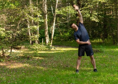 Parkta koşan bir sporcu ormanda, meşe ağaçları yeşil çimenler atletik sporculara dayanan koşucu tabiatı, açık hava eğitim eğlencesi. Yetişkin vücudu çapraz, mesafe