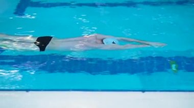 Spor havuzundaki profesyonel yüzücü sağlıklı bir yaşam tarzı konsepti olan yüzme şapkası genç ve kaslı bir başlangıçtan gelen felç için yavaşça sporcuları yüzdürür. Derin serbest stil boşalt