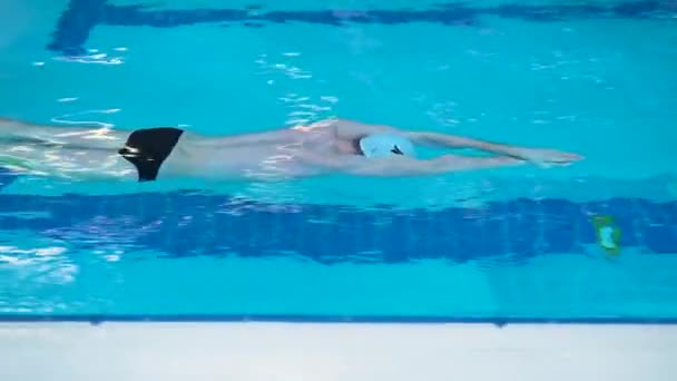 Nadador profesional en una piscina deportiva concepto de estilo de vida saludable gorra de natación flota lentamente atleta, para el accidente cerebrovascular salpicaduras de inicio joven y muscular, la recreación sin miedo. Ventilación estilo libre profundo — Vídeo de stock