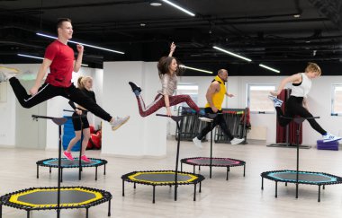 Trambolinde spor yapan kadın ve erkek grubu, fitness antrenmanı, sağlıklı yaşam, trambolin grubu batut kız sağlığı konsepti, spor salonunda formda bir takım ve genç insan, gülümseyen mutluluk.