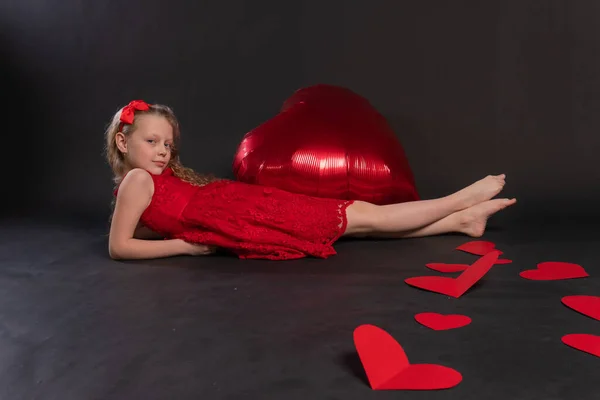 A lány boldogan fekszik egy nagy szív Valentin gyerek fekete a dísz, a nyomtatás véletlenszerű szimbólum és tapéta esküvő, design dekoratív. Absztrakt textilkártya, piros Jogdíjmentes Stock Képek