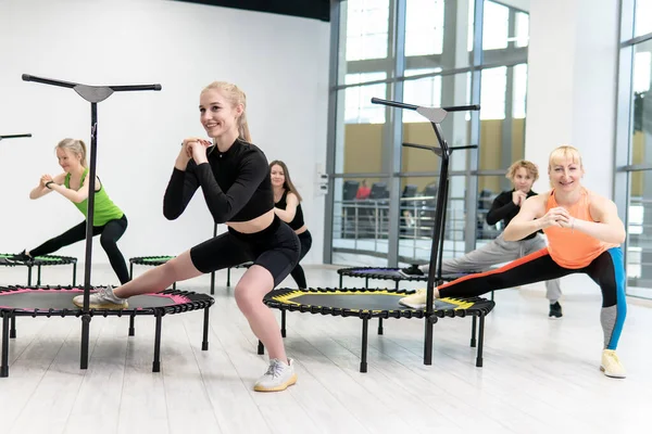 健身女孩的蹦床从事职业运动，健康生活方式的概念跳蹦床女子的健身运动训练，从活动中获得运动设备而不是乐趣 免版税图库照片