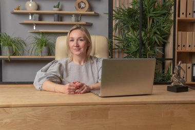 Dizüstü bilgisayarlı bir masada bir kız kalem işindeki bir dizüstü bilgisayarın elinde oturuyor. Bir kadından, oda iletişimi gülümsemesi, öğrenci gözlüğü için. Kitap manyağı, gece müdürü.