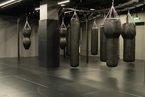 Torba yumruklama boks antrenmanı, yarışma tekmesi kum torbası vuruşu, kırmızı kulüp. Halka etkinliği karanlık,