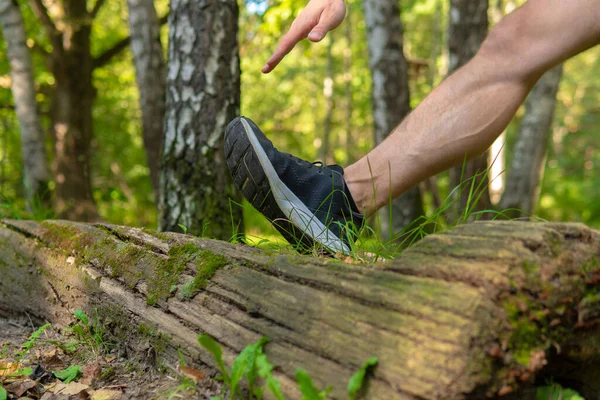Egy fiatal, kitartó sportoló nyújtózkodik az erdőben a szabadban, az erdő körül, tölgyfákkal.fuss sportoló életmód kocogó fiatal rekreációs férfi, ember. Felnőtt szabadidő kereszt, nyújtás Stock Fotó