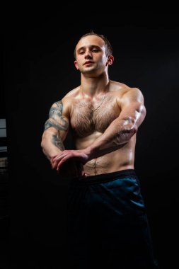 Siyah arka plandaki adam ağırlık kaldırarak, güçlü bir şekilde vücut kaslarını şişirmeye devam ediyor. Kaldırma gücü, beden eğitimi.