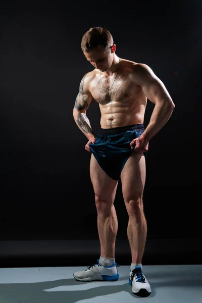 Άντρας σε μαύρο φόντο κρατά αλτήρες αντλείται σε fitness bodybuilding στήθος άσκηση bodybuilder αρσενικό Young μέταλλο, ένα ταιριάζει μυς στον κορμό του κοιλιακούς και τα πόδια δικέφαλους κατά την ανάπτυξη ρολό — Φωτογραφία Αρχείου