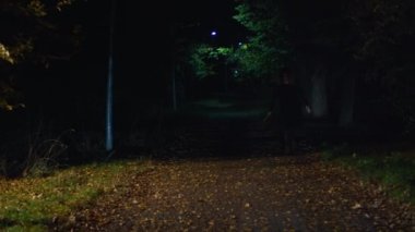 Elinde çekiçle parkta yürüyen ürkütücü bir kadın.