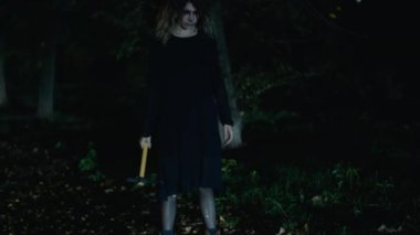 Elinde çekiçle parkta yürüyen ürkütücü bir kadın.