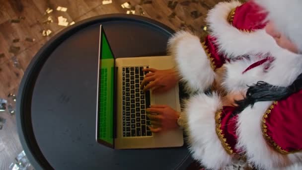 En glad kvinna som mrs Santa kommunicerar på sin dator på julkontoret. Semester i karantän. distanskommunikation, semestergåvor och rabatter. — Stockvideo