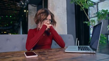 Masasında bilgisayar ve telefonla oturan bir kadın.