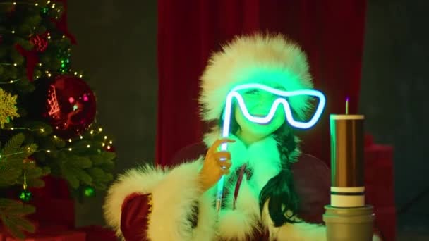 Donna felice in costume da Babbo Natale gioca con tubi al neon vicino alla bobina tesla, sullo sfondo dell'albero di Natale. Spettacolo di Capodanno, vacanze per bambini. — Video Stock