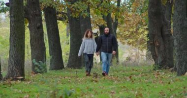 Sonbahar ormanlarında mutlu genç bir çift yol boyunca yürüyor..