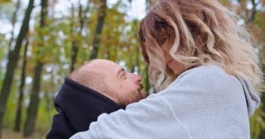 Sonbahar ormanlarında mutlu genç bir çift duygularını gösterir, oynaşırlar, sarılırlar..