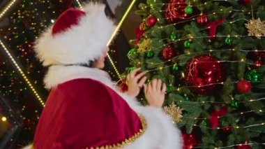 Mutlu kadın Noel Baba Noel ağacını Noel ofisinde süslüyor. Karantinada tatiller. Uzaktan iletişim, tatil hediyeleri ve indirimler.