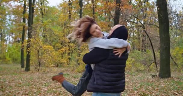 Happy young couple in the autumn forest show their feelings, fool around, hug. — Stock Video