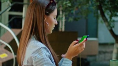 Genç bir kadın telefonda konuşmaktan hoşlanır, biriyle mesajlaşmaktan, harika bir yerde, beyaz bir tişörtle oturmaktan.