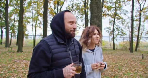 Щасливий хлопець і молода жінка п'ють чай в лісі восени, ходять в лісі . — стокове відео