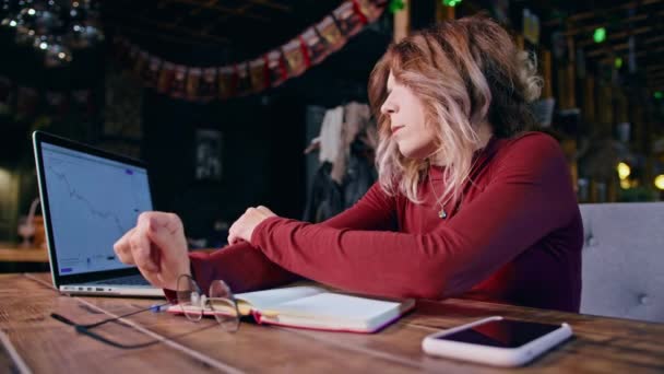 Mujer sentada en una mesa con un portátil — Vídeos de Stock