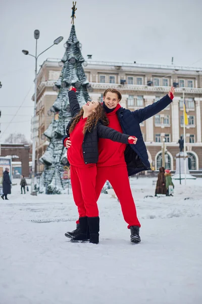 Genç bir aile babası ve kız, karlı bir günde günü parkta geçirirler. Kış şehrinde yürürken eğlenen duygusal genç çift, neşeli bir adam, gülen güzel kadınına sarılır.. — Stok fotoğraf
