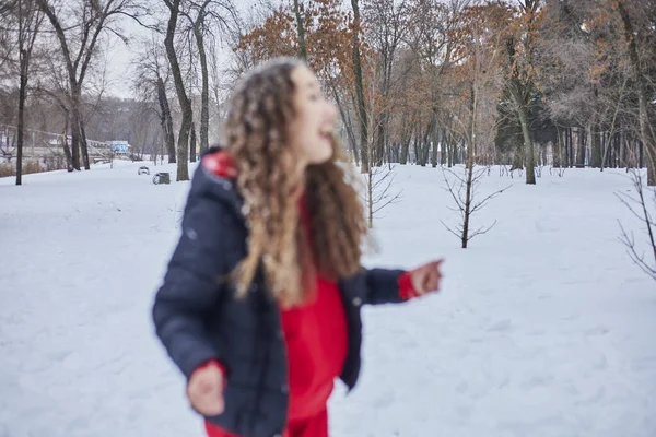 Una joven feliz mujer se está divirtiendo en un parque de invierno, lanzando nieve, hace frío en sus manos, las emisiones están fuera de escala. —  Fotos de Stock