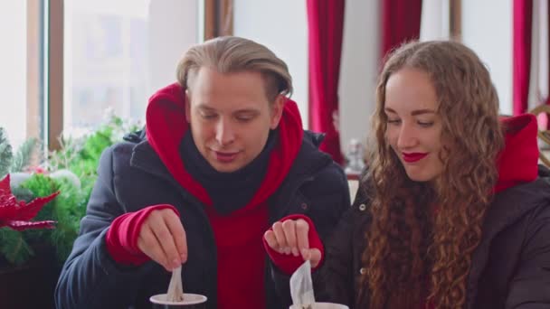 A guy and a girl drink tea in a cafe in winter — Vídeo de Stock
