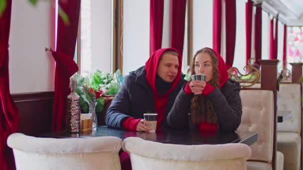 A guy and a girl drink tea in a cafe in winter — Vídeo de Stock