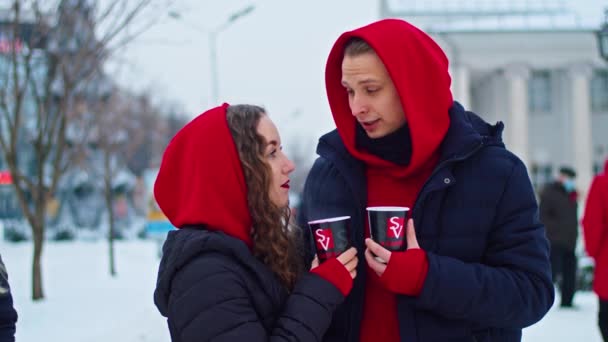 Krivoy Rog, Ukraine - 01.01.22 young family guy and girl spend the day in the park on a snowy day. the guy hugs the girl while standing on the street, they drink coffee together. — Video Stock