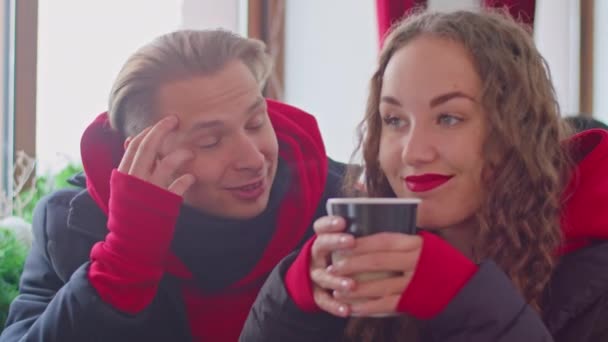 Ένας άντρας και ένα κορίτσι πίνουν τσάι σε ένα καφέ το χειμώνα. — Αρχείο Βίντεο